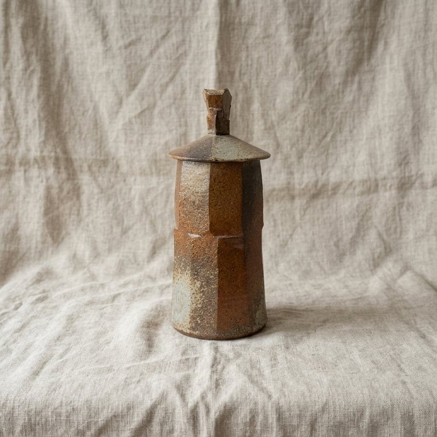 The same ceramic jar resting on folded natural linen